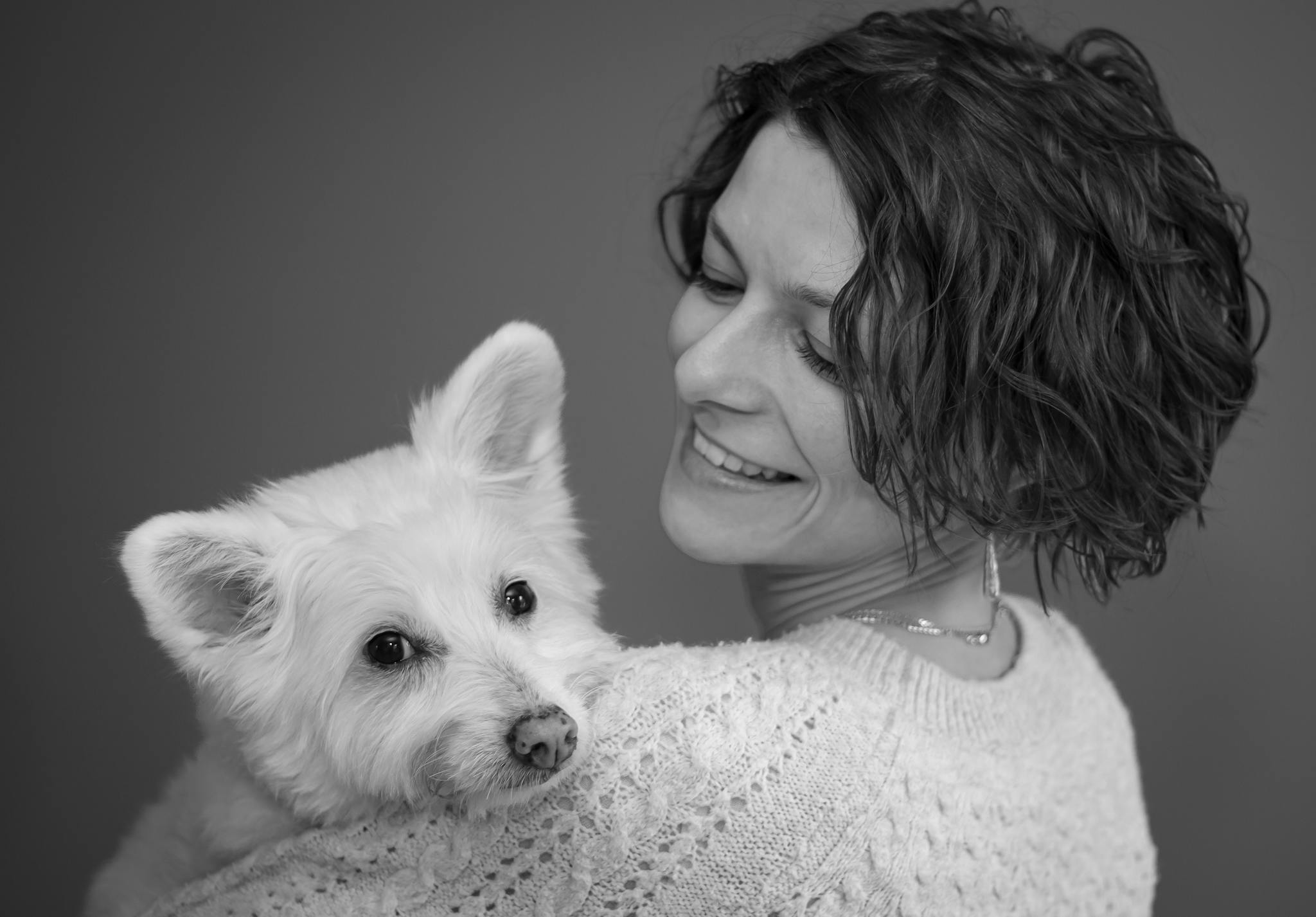 Close-up black and white portrait of smiling woman holding her dog.